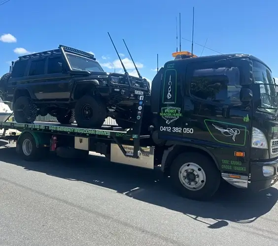 Port Macquarie Towing tilt tray truck transporting a 4WD vehicle on flatbed deck for emergency roadside breakdown recovery in Port Macquarie.